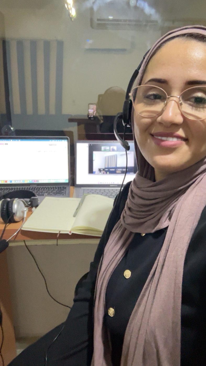 Marwa at an interpreting desk with two laptops