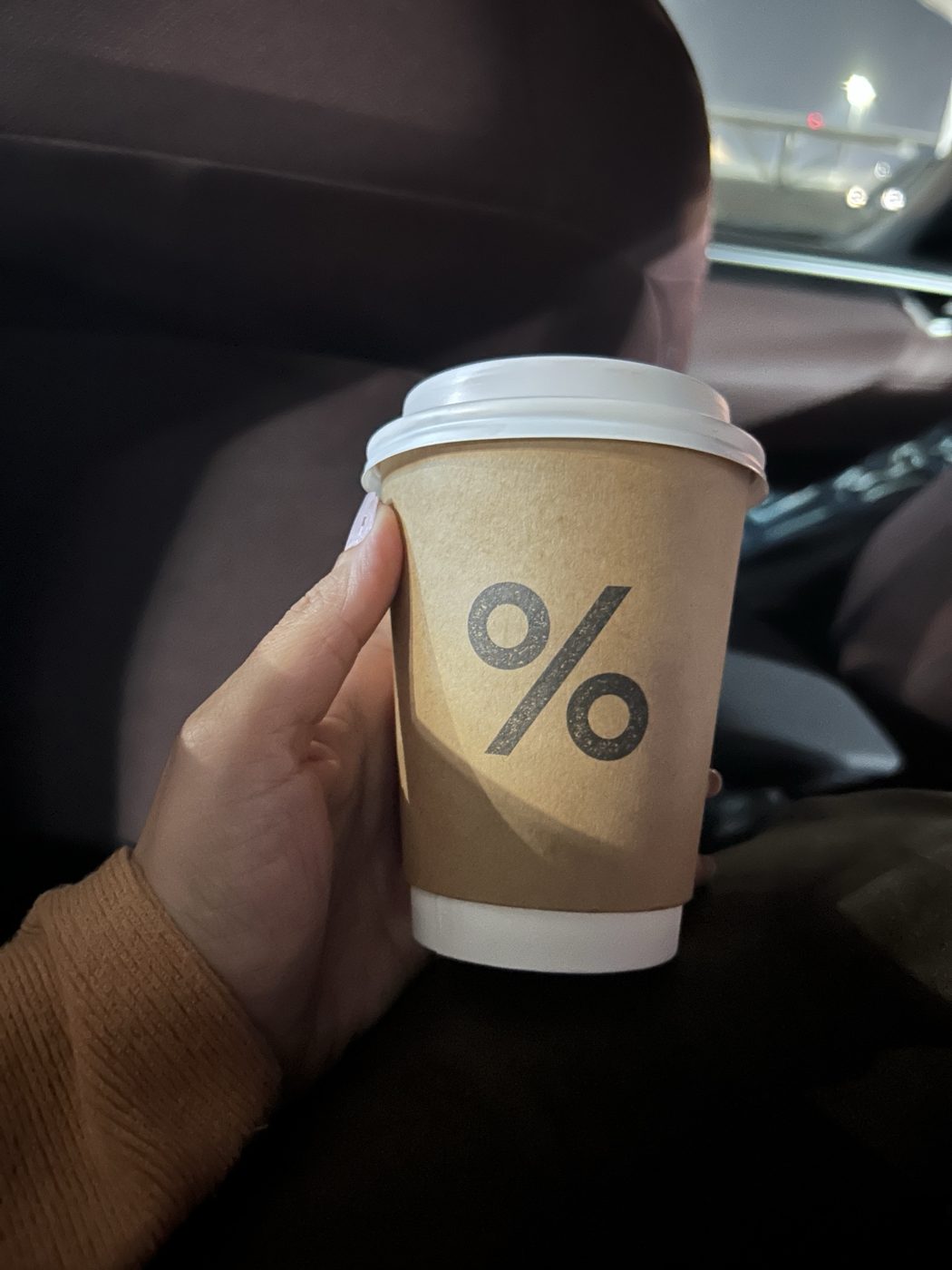 A takeaway coffee cup held in a car